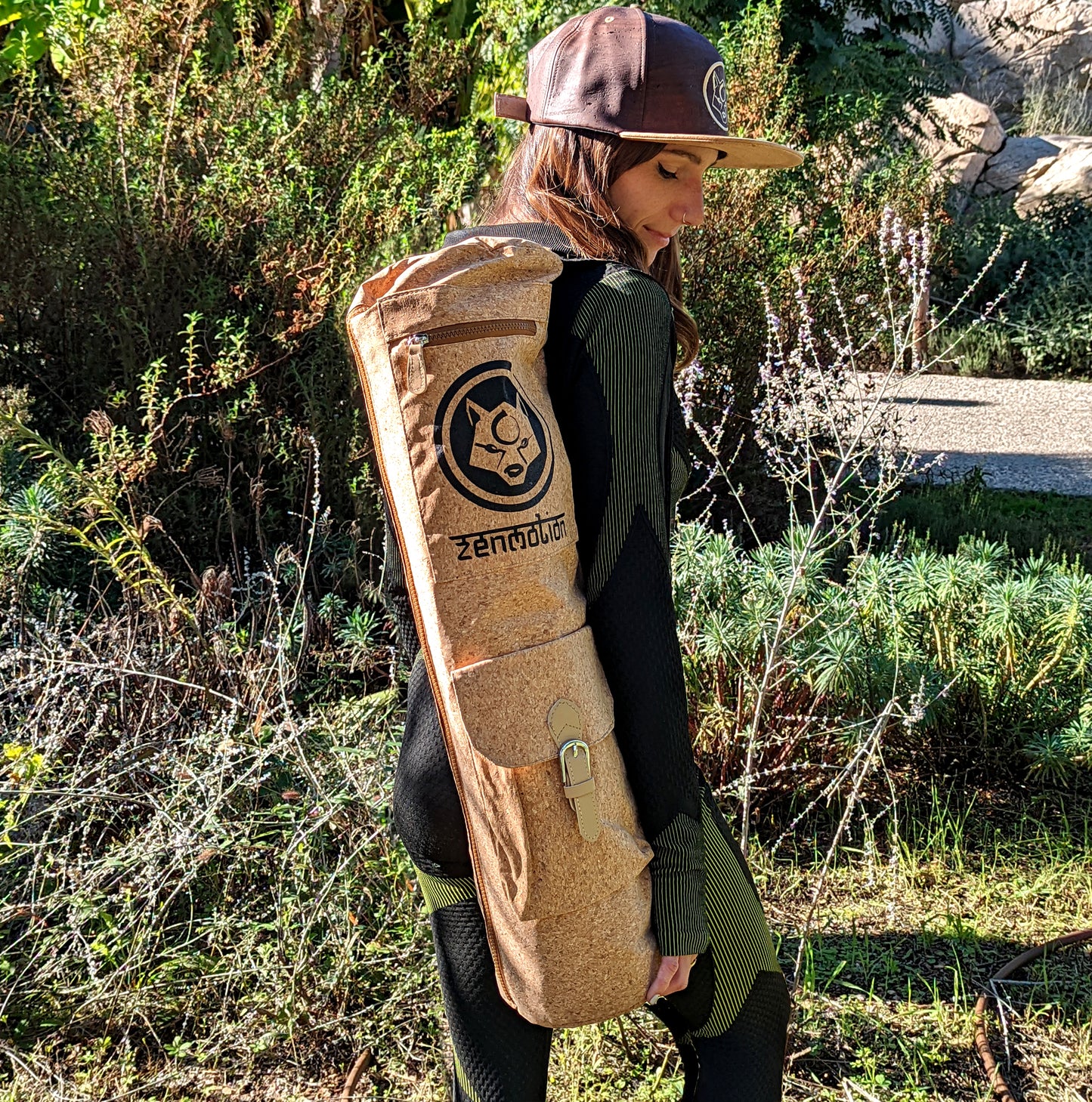 A picture of a girl wearing a ZenMotion cork hat and holding a ZenMotion Deluxe Cork Mat Bag.