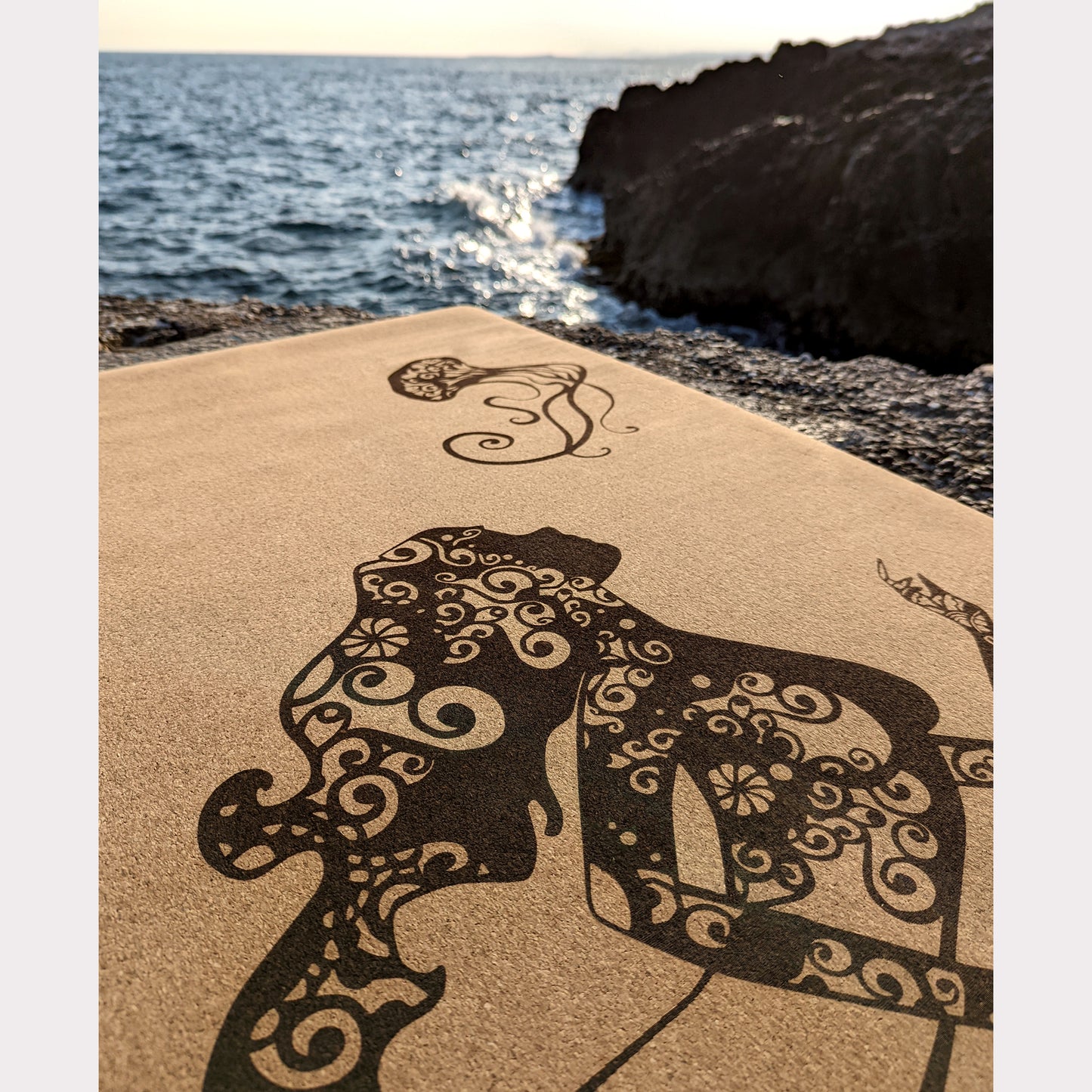 Close-up of the top of the Sea Fairy ZenMotion cork yoga mat placed against a tranquil sea background.